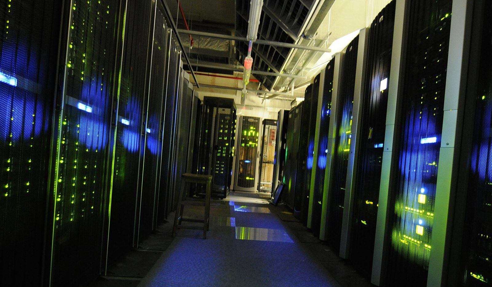 Blue lit server room aisle lined with equipment racks